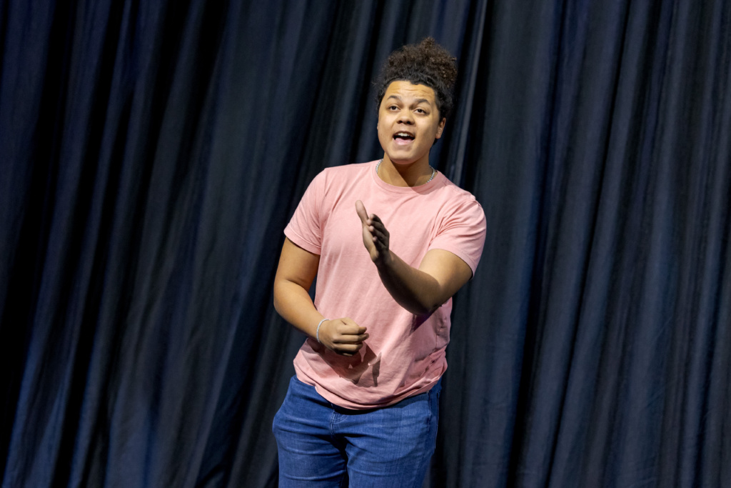 An actor on stage in front of a curtain.